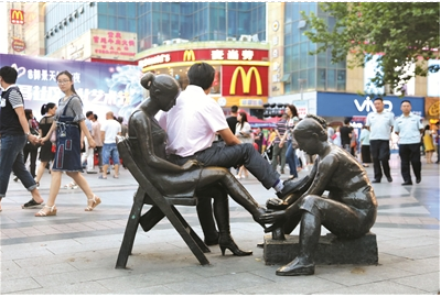 宜昌街头现不文明现象 男子若无其事坐在雕塑上
